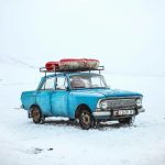 Classic blue car in snowy winter scene, Ak-Talaa District, Kyrgyzstan.